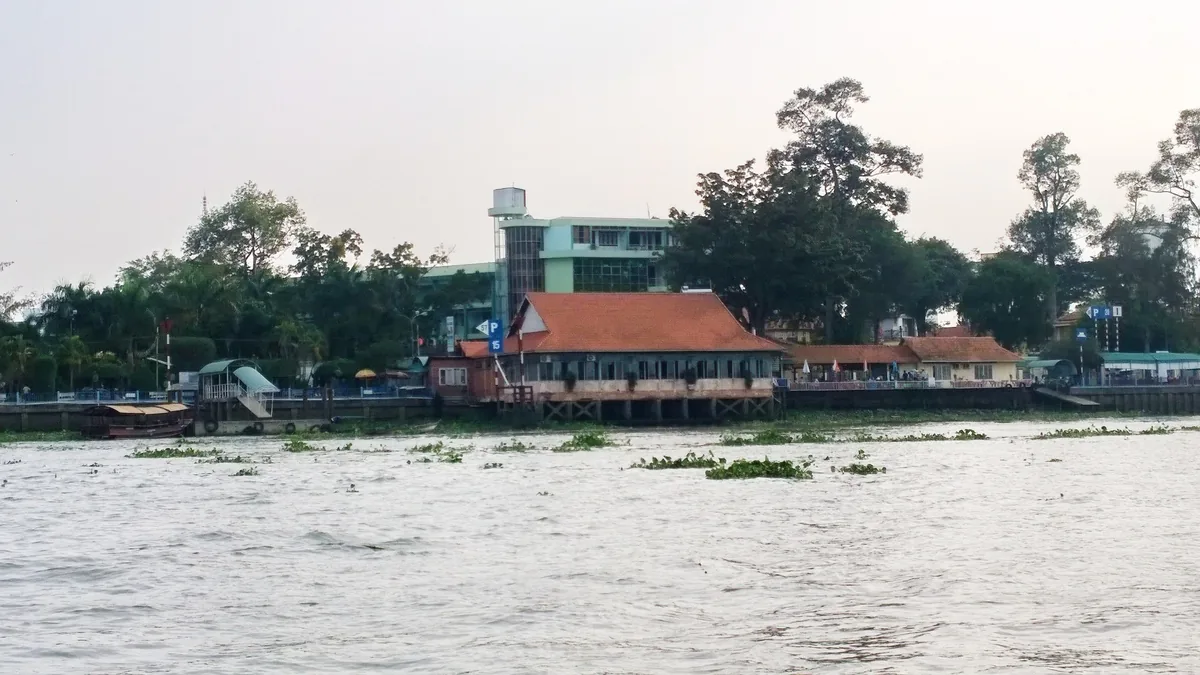 Ngôi nhà mái ngói đỏ ven sông cùng cây xanh trên bờ sông rộng gần An Bình, Vĩnh Long.